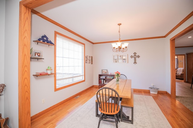 dining space with a notable chandelier, light wood finished floors, visible vents, and crown molding