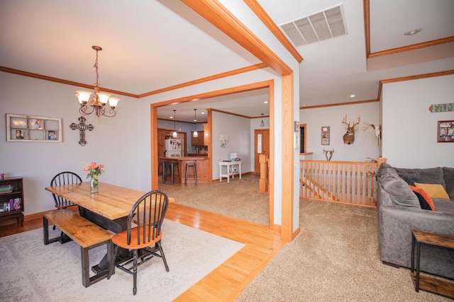 dining area with a notable chandelier, crown molding, visible vents, and wood finished floors