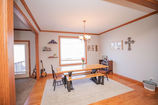 dining area featuring light wood-style flooring, ornamental molding, a chandelier, and baseboards