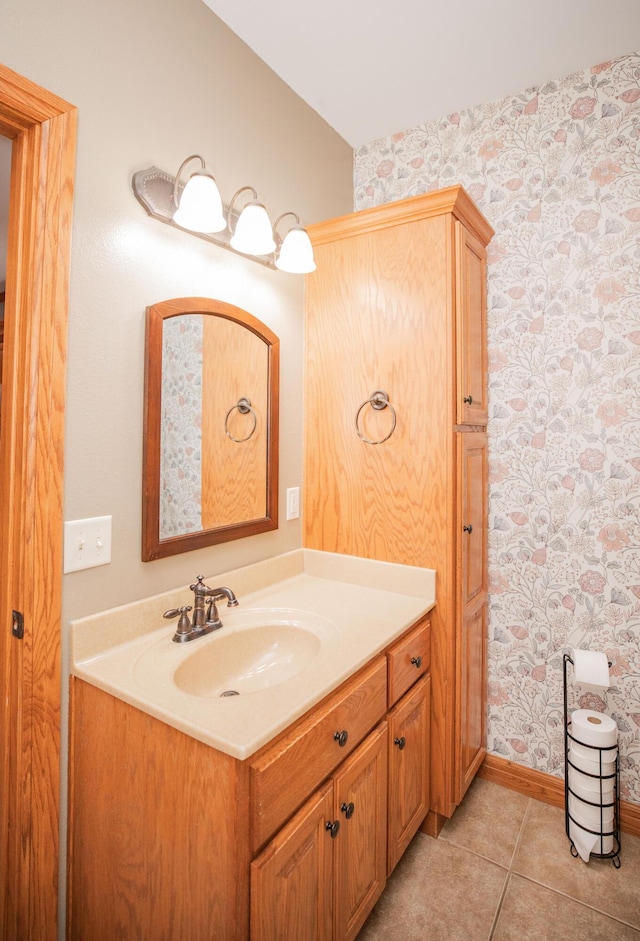 bathroom featuring wallpapered walls, vanity, baseboards, and tile patterned floors