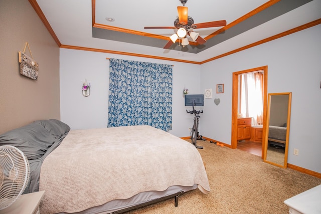 carpeted bedroom with ceiling fan, connected bathroom, baseboards, ornamental molding, and a tray ceiling