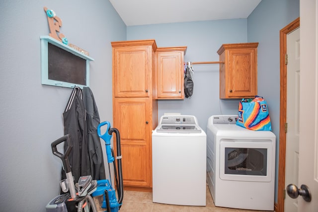 clothes washing area with light tile patterned floors, washing machine and dryer, and cabinet space