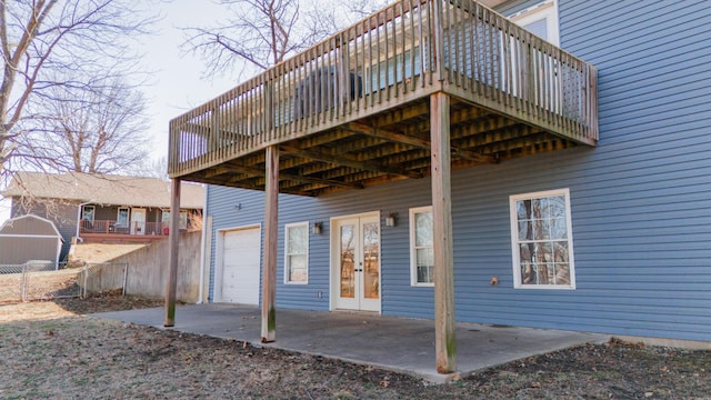 exterior space with a deck, french doors, fence, and a garage