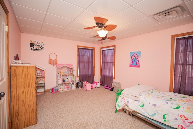 bedroom with carpet, visible vents, ceiling fan, and a drop ceiling