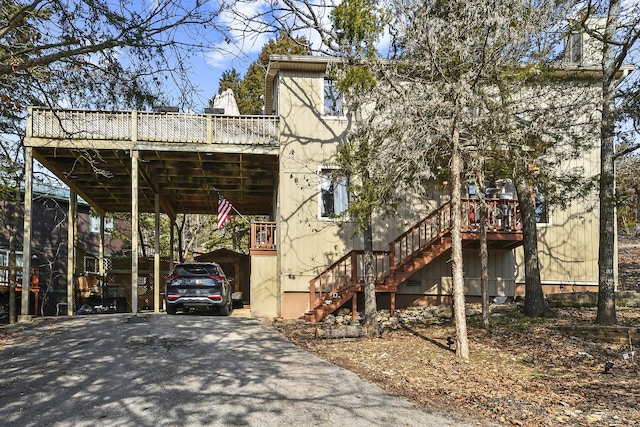 exterior space with stairs, a carport, and aphalt driveway