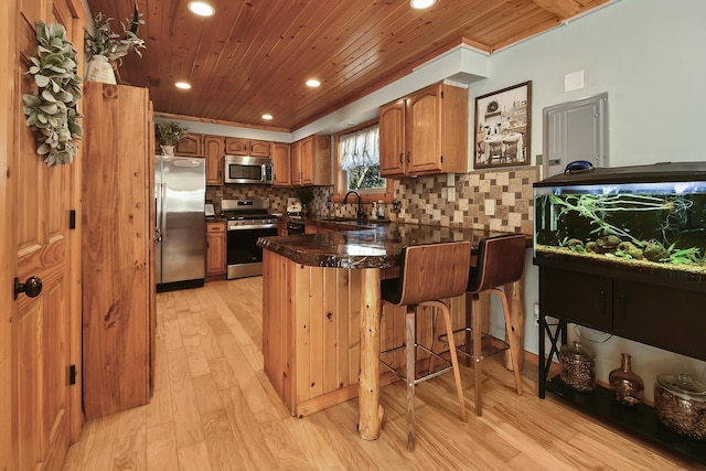 kitchen featuring a peninsula, appliances with stainless steel finishes, a sink, and wood ceiling