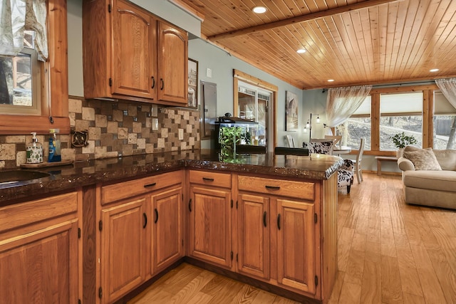 kitchen featuring a peninsula, wood ceiling, light wood-style floors, brown cabinets, and tasteful backsplash