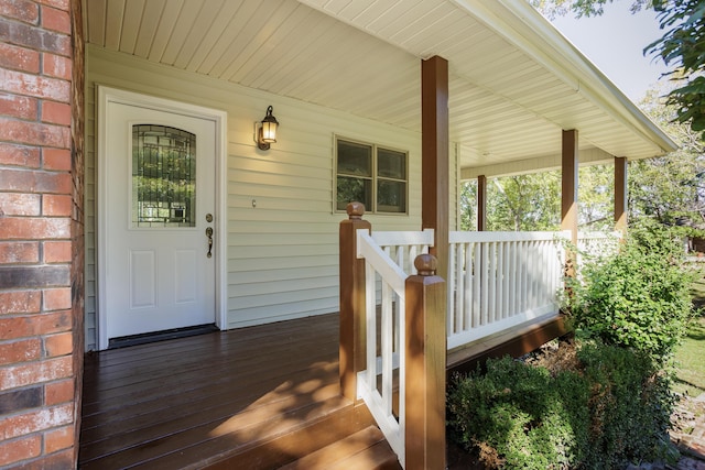 doorway to property with covered porch and brick siding