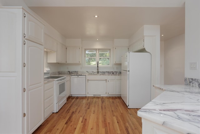 kitchen with white appliances, white cabinets, light stone counters, light wood-type flooring, and a sink