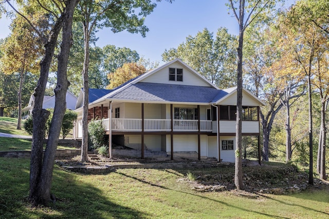 back of property with a sunroom, a shingled roof, and a lawn