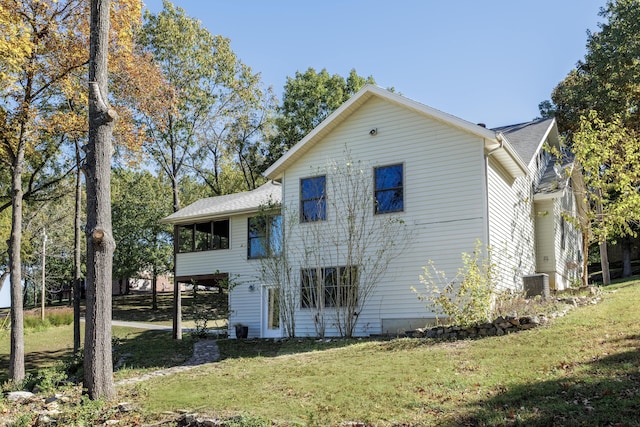 view of front of property with central air condition unit, a sunroom, and a front yard