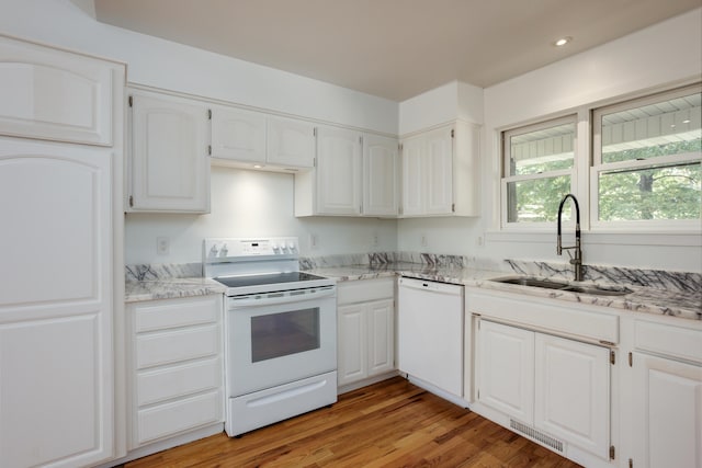 kitchen with light stone counters, visible vents, white cabinets, a sink, and white appliances