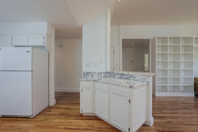 kitchen featuring light wood finished floors, freestanding refrigerator, and white cabinetry