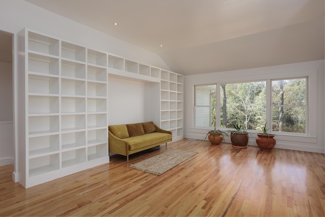 sitting room with built in features, light wood-type flooring, and lofted ceiling