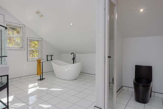 full bathroom featuring tile patterned flooring, a soaking tub, and lofted ceiling