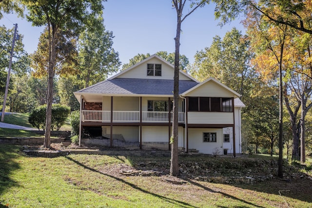 rear view of property featuring a shingled roof, a lawn, and a sunroom