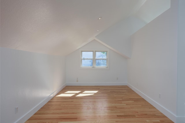 bonus room featuring vaulted ceiling, light wood finished floors, a textured ceiling, and baseboards