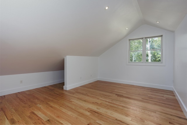 bonus room featuring light wood-style flooring, baseboards, and vaulted ceiling