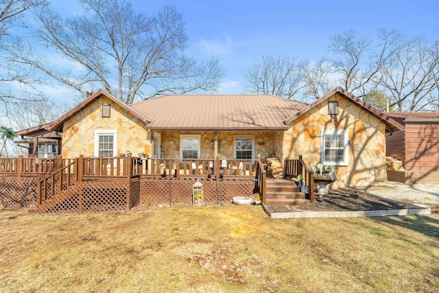 view of front of home featuring covered porch, stone siding, a front lawn, and metal roof