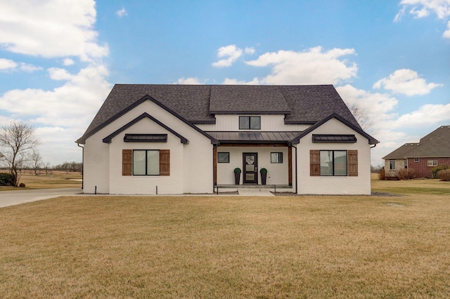 exterior space with a standing seam roof, metal roof, a front lawn, and roof with shingles