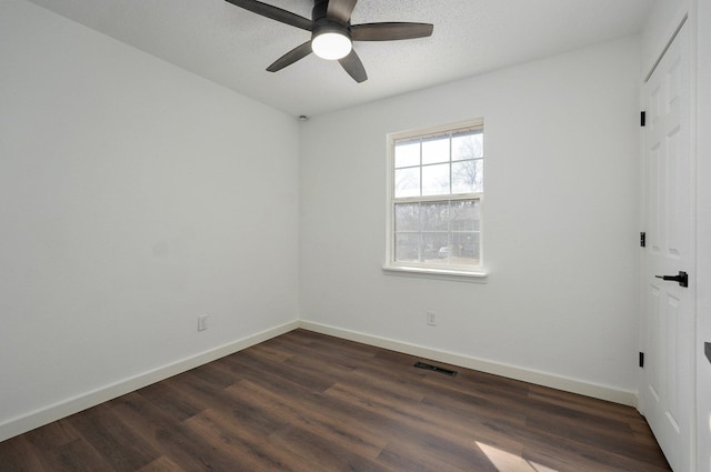 unfurnished room featuring baseboards, visible vents, ceiling fan, and dark wood-type flooring