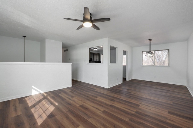 empty room featuring a textured ceiling, dark wood finished floors, a ceiling fan, and baseboards