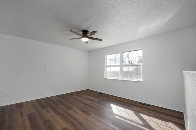 spare room featuring a textured ceiling, visible vents, a ceiling fan, baseboards, and dark wood-style floors