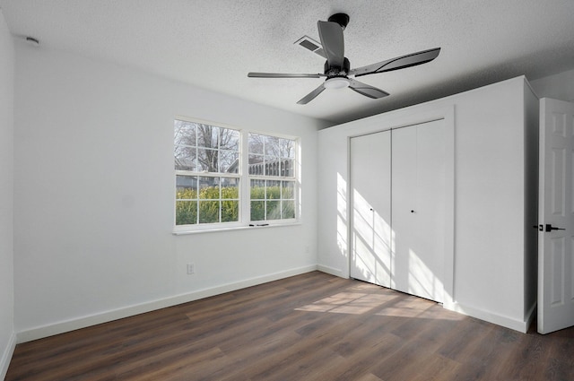 unfurnished bedroom with a textured ceiling, a closet, baseboards, and wood finished floors