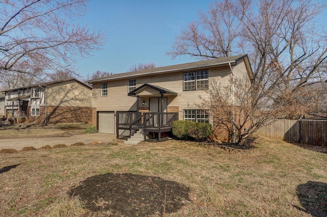 raised ranch featuring a garage, brick siding, fence, driveway, and a front yard