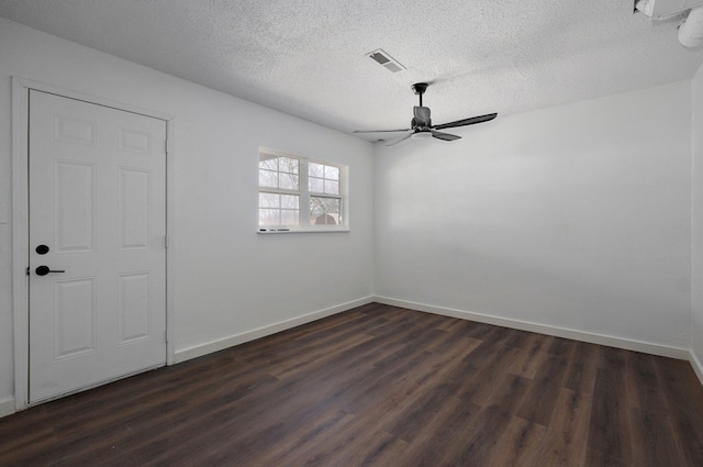 spare room featuring dark wood-style flooring, visible vents, a textured ceiling, and baseboards