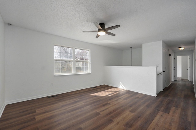 empty room featuring dark wood-style floors, ceiling fan, a textured ceiling, and baseboards