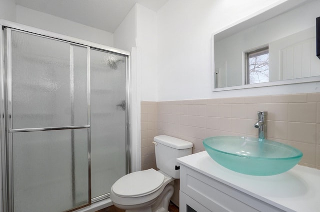 full bath featuring toilet, a stall shower, vanity, and wainscoting