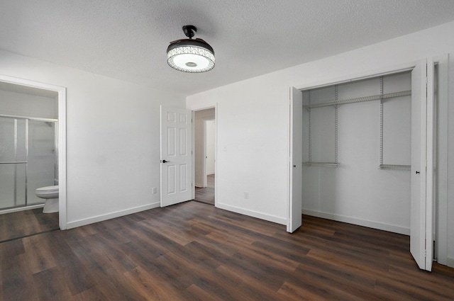 unfurnished bedroom featuring dark wood-type flooring, a closet, a textured ceiling, and baseboards