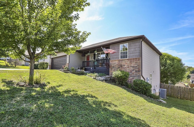 view of front of home featuring a garage, fence, a front lawn, and brick siding