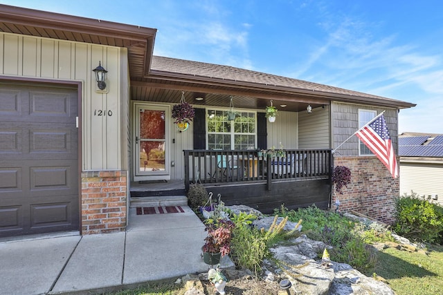 doorway to property featuring covered porch, brick siding, board and batten siding, and an attached garage