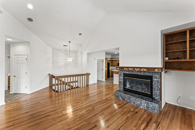 living room with a premium fireplace, high vaulted ceiling, wood finished floors, and recessed lighting