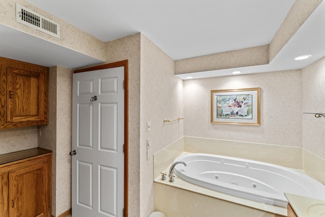 bathroom with a jetted tub, wallpapered walls, and visible vents