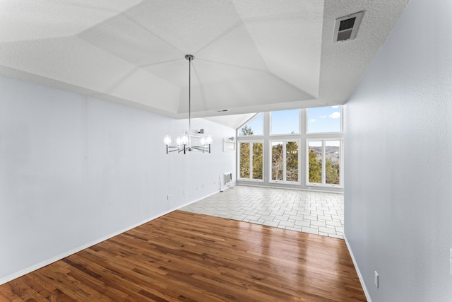 unfurnished dining area featuring lofted ceiling, visible vents, a textured ceiling, and wood finished floors