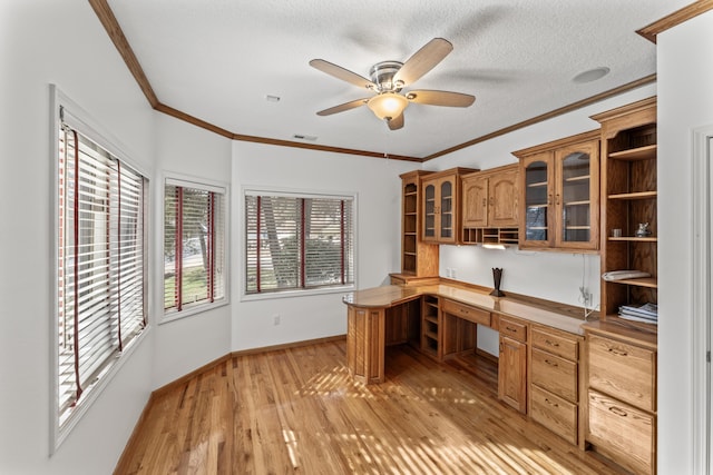 unfurnished office with built in desk, ceiling fan, a textured ceiling, light wood-type flooring, and baseboards