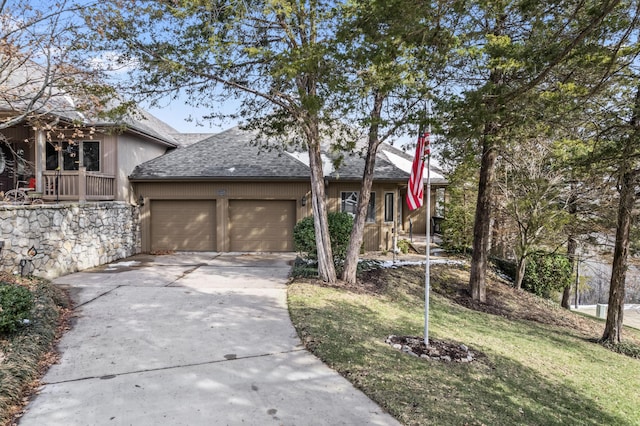 view of front of house featuring a garage, concrete driveway, a front lawn, and roof with shingles