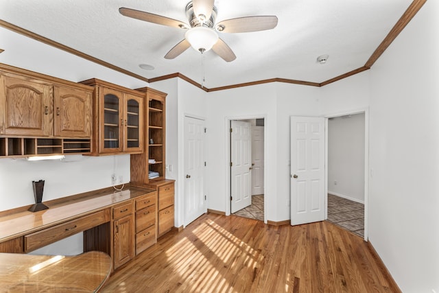 unfurnished office with crown molding, ceiling fan, and light wood-style floors