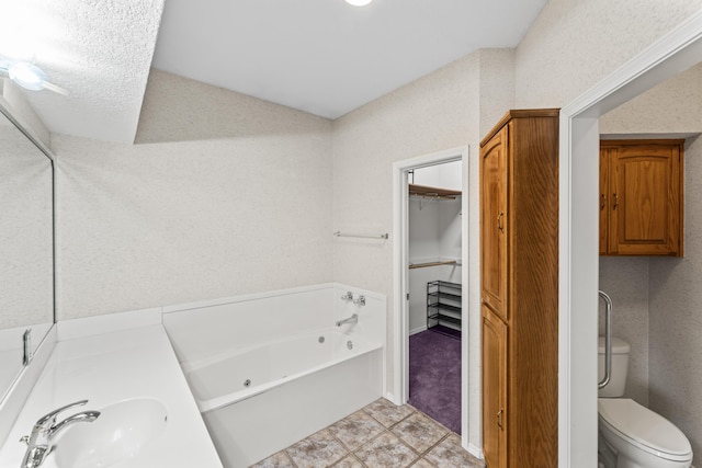 full bathroom featuring a jetted tub, toilet, a walk in closet, and a sink