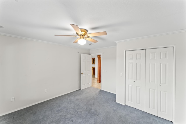 unfurnished bedroom featuring ceiling fan, baseboards, ornamental molding, a closet, and carpet