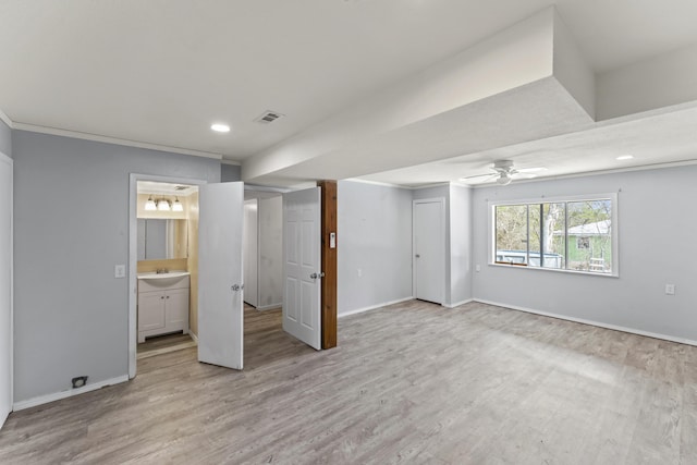 interior space with crown molding, visible vents, light wood-style flooring, a sink, and baseboards