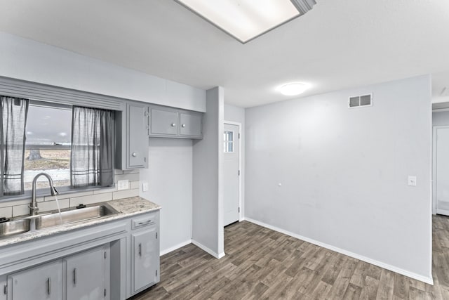 kitchen with a sink, visible vents, light countertops, gray cabinets, and dark wood-style floors