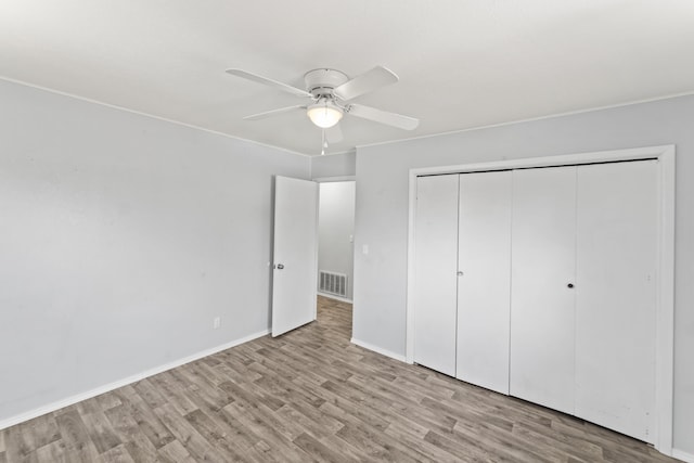 unfurnished bedroom with a closet, visible vents, baseboards, and wood finished floors