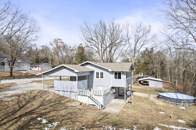 view of front of home featuring a shingled roof and an outdoor pool