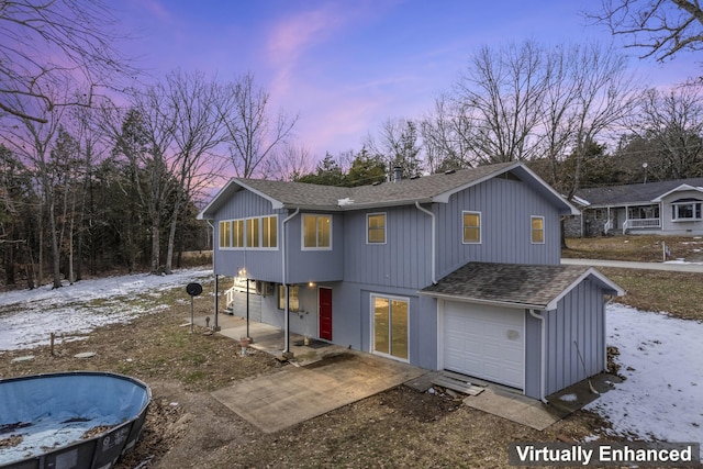 view of front of house with an attached garage, a patio, and roof with shingles