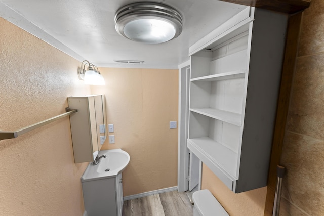 bathroom with visible vents, a textured wall, vanity, and wood finished floors