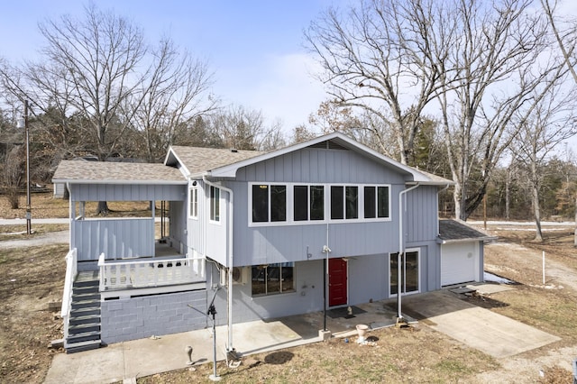 view of front facade featuring a garage, concrete driveway, stairway, and roof with shingles